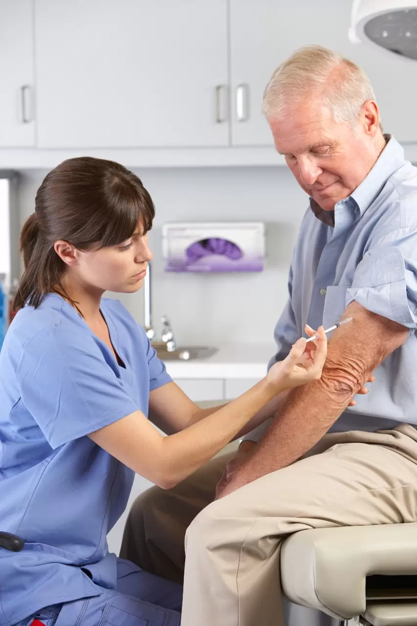 A nurse is giving an older man something to put on his arm.