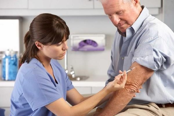 A nurse is giving an arm injection to a man.