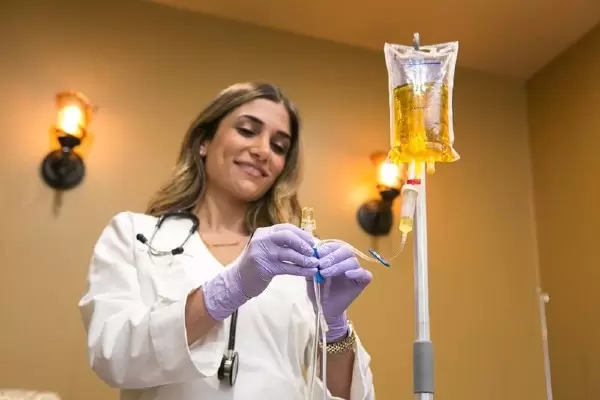 A woman in white lab coat holding a needle.