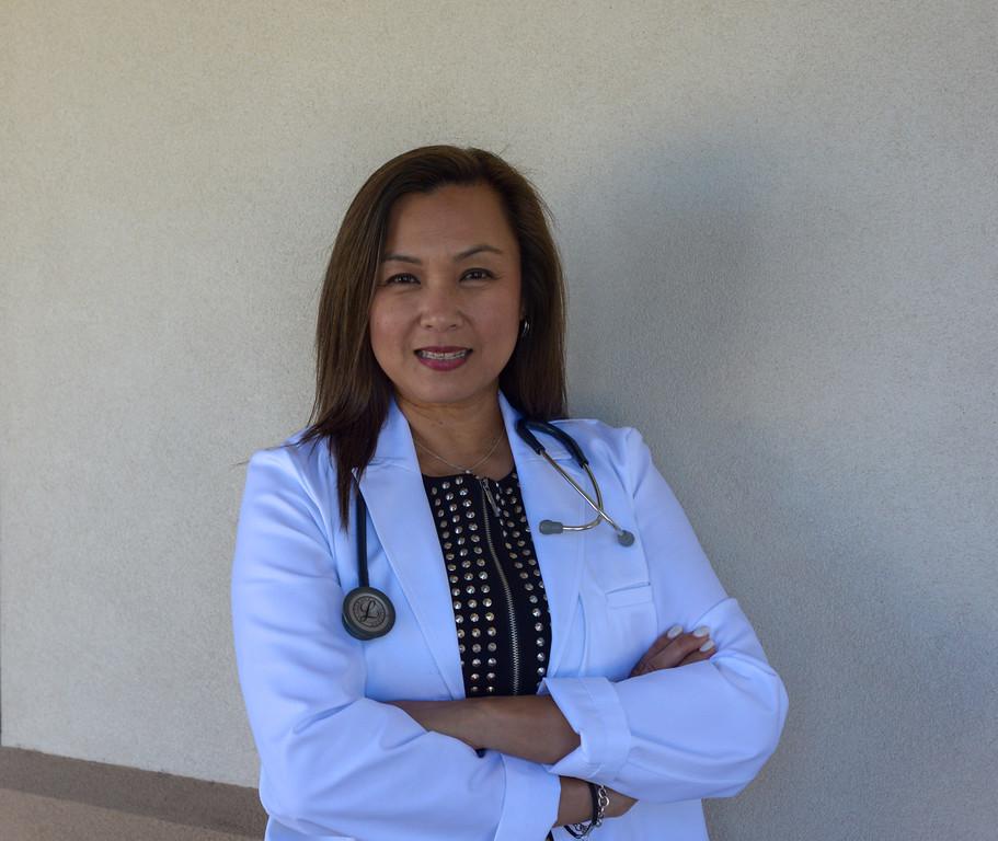 A woman in white coat standing next to wall.