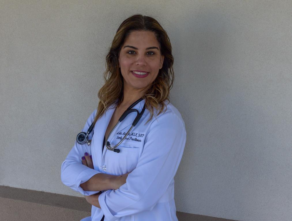 A woman in white lab coat standing with her arms crossed.