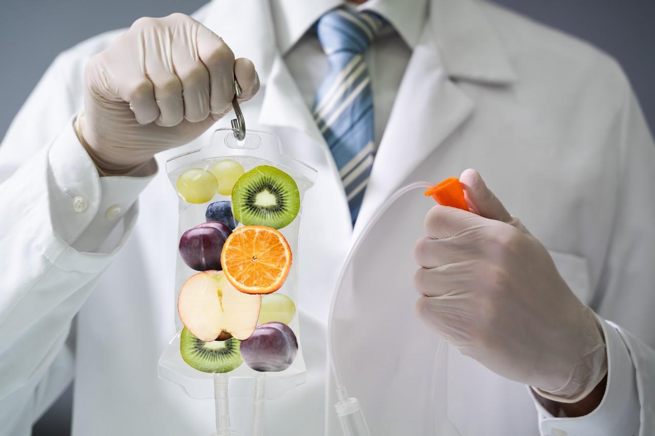 A doctor holding an orange and some fruit