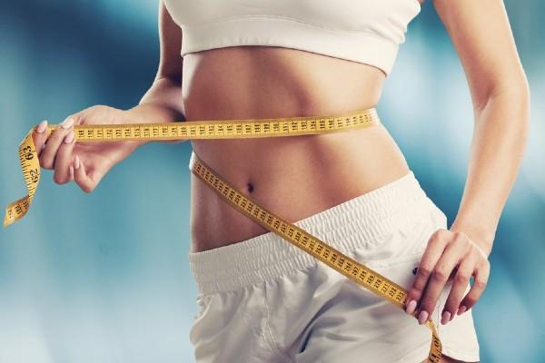 A woman is holding a tape measure around her waist.