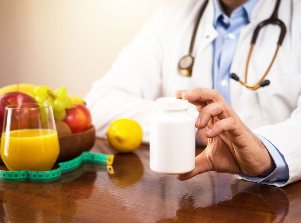 A doctor holding a cup of coffee near some fruit.